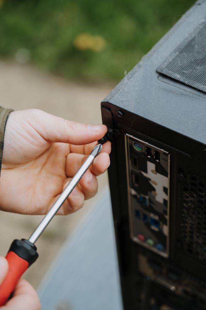 features-03 Close-up of a person tightening screws on a PC case for maintenance.