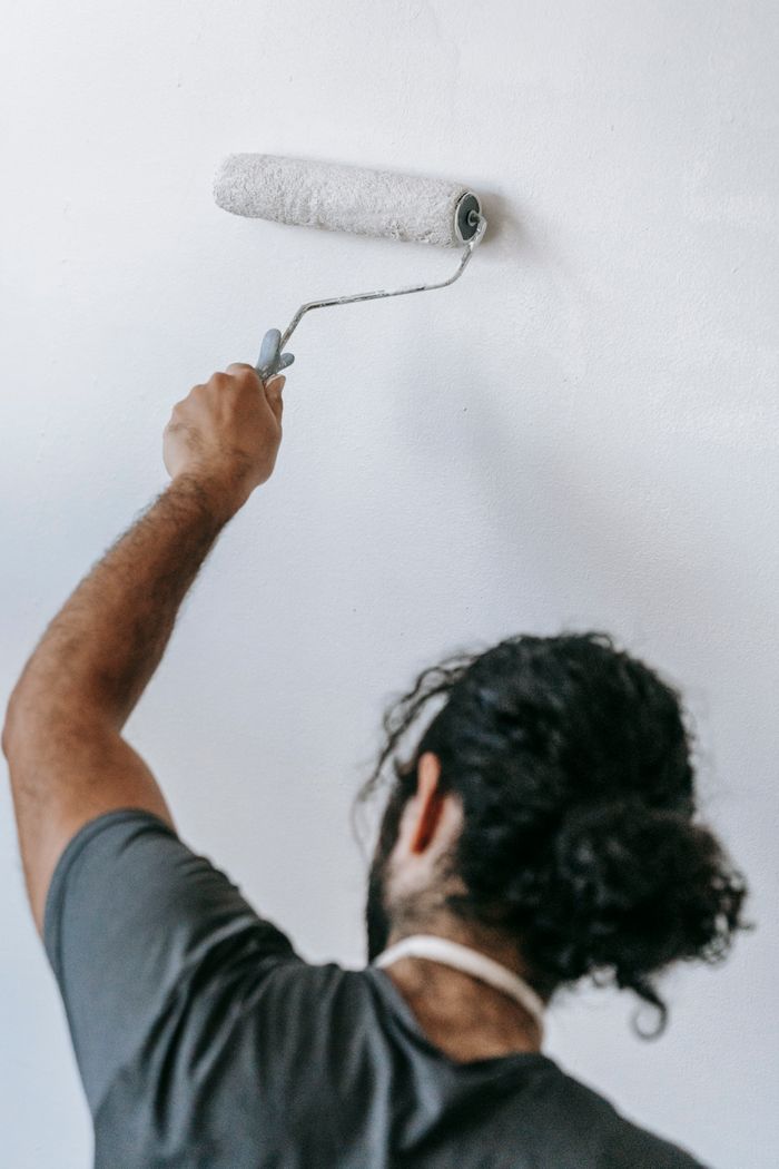 Crafting Captivating Headlines: Your awesome post title goes here A man painting a wall white with a roller, focusing on home renovation.