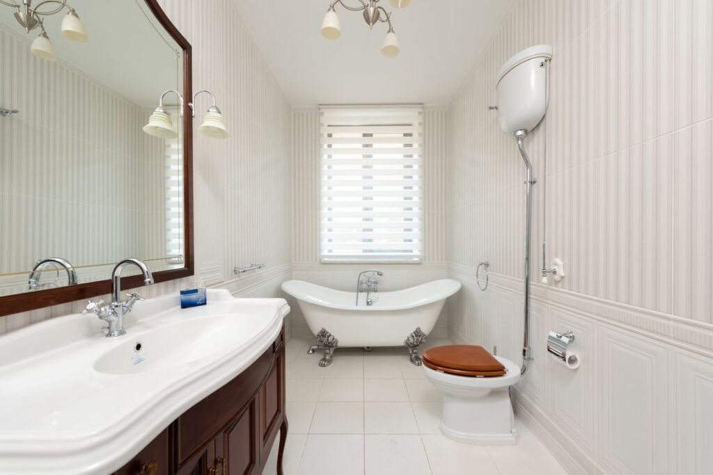 Services Spacious bathroom featuring a classic clawfoot tub, vanity, and wooden toilet seat.