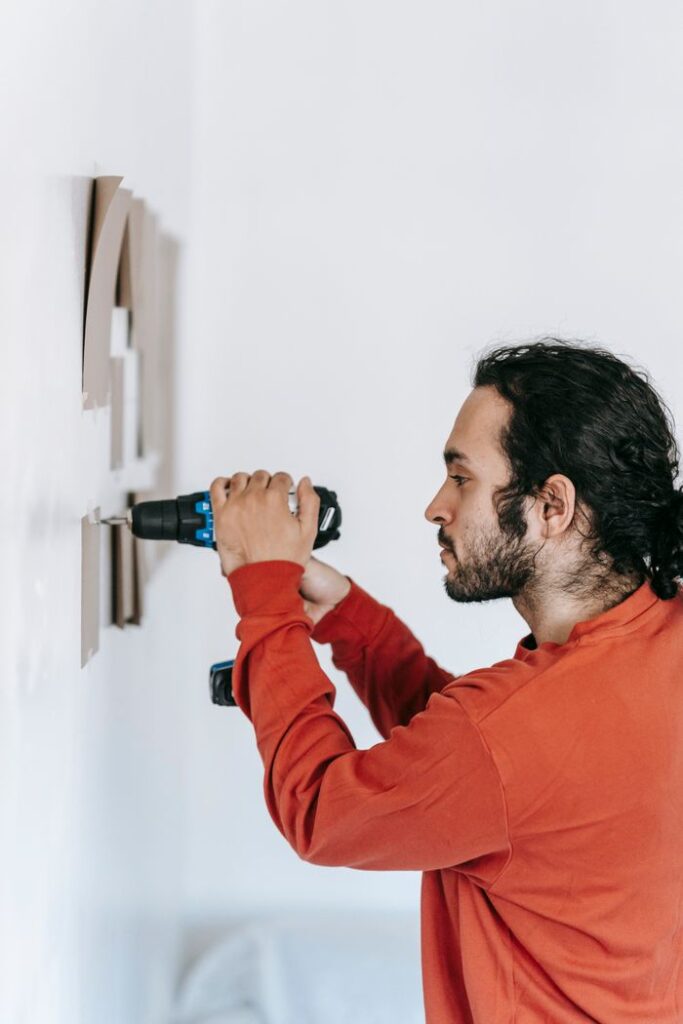 Services Focused man drilling into wall, enhancing home interiors with precision tools.